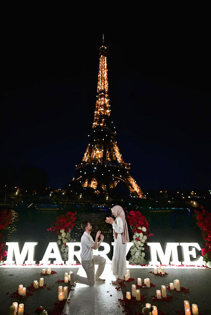 Demande en mariage féerique avec bougies, pétales, lettres lumineuses MARRY ME et tour Eiffel scintillante