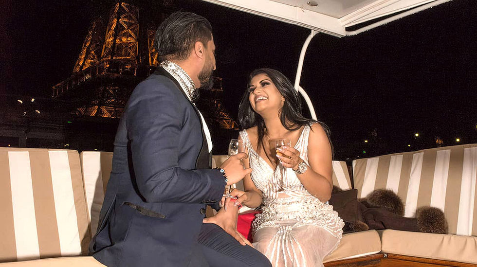 Une femme et un homme se regardent avec amour dans un bateau sur la Seine à Paris, avec vue sur la Tour Eiffel illuminée