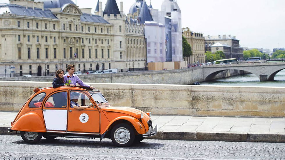 Citroen 2CV orange avec couple d'amoureux traversant un pont de Paris