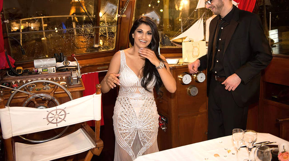 Une femme brune en robe blanche sourit en découvrant l'intérieur d'un yacht parisien