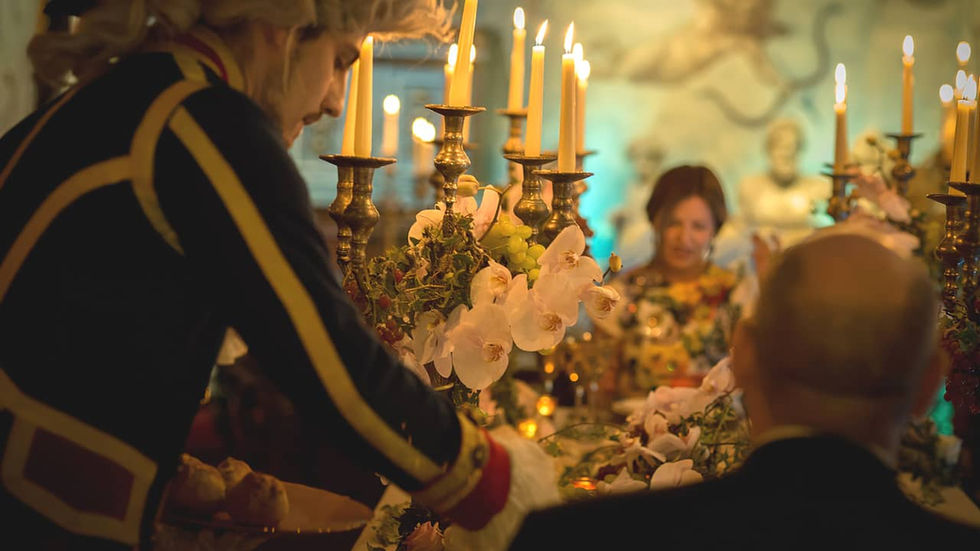 Serveur en tenue du 18ème siècle et avec perruque poudrée servant du champagne à un couple d'amoureux