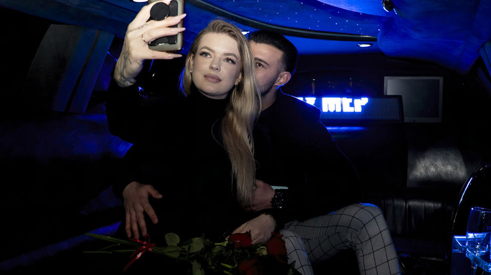 De nuit, deux amoureux prennent un selfie dans une limousine après une demande en mariage à Paris