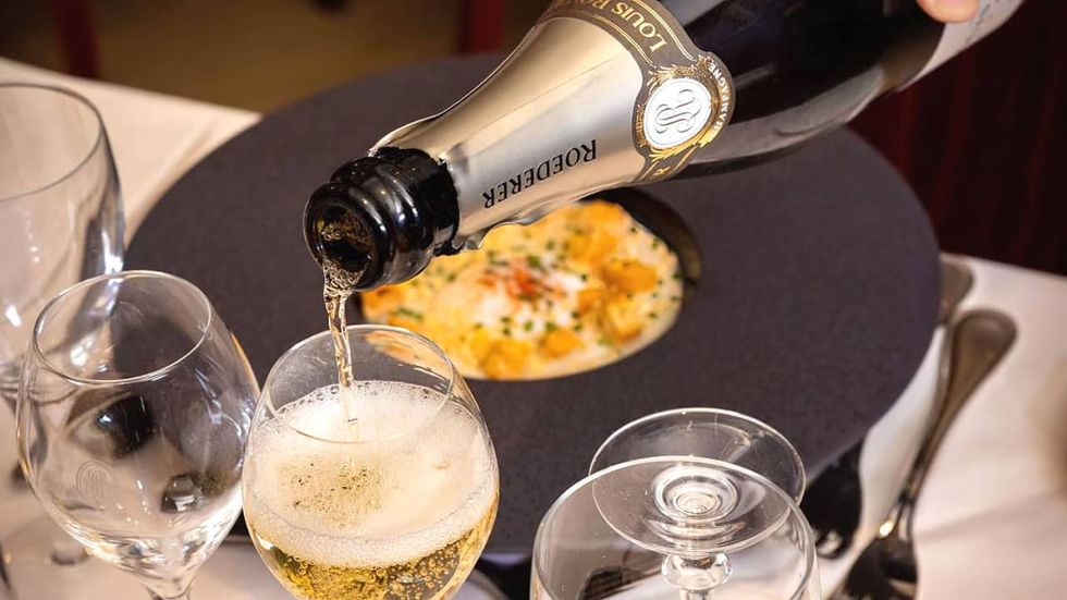 Champagne versé dans un verre sur une table avec plat gastronomique dans une assiette noire