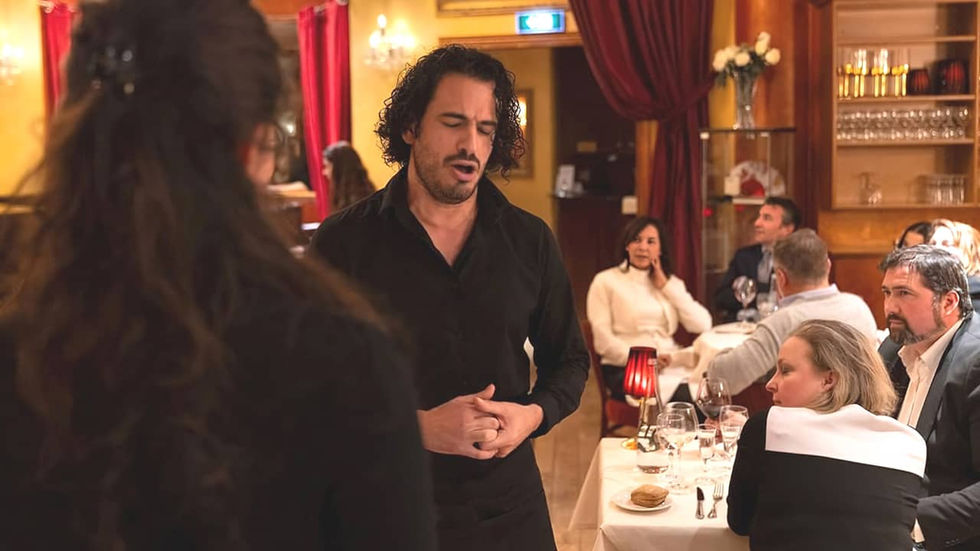 Homme en tenue noire chantant dans un restaurant romantique de Paris
