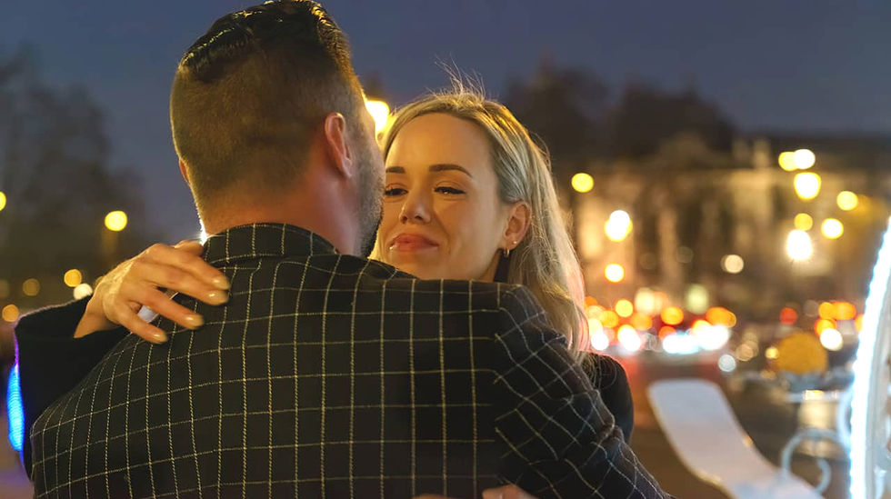 Femme blonde émue, les larmes aux yeux, regardant son partenaire avec amour lors d'une demande en mariage