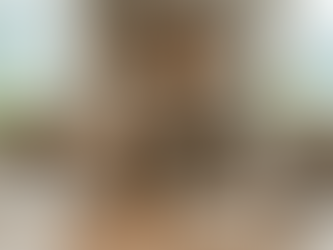 Nika von VeroVitalis sitzt lächelnd an einem Holztisch in einem hellen Raum und gibt einen Cordyceps-Flüssigextrakt in ein Glas Wasser. Vor ihr liegen getrocknete Cordyceps-Pilze, ein offenes Fachbuch mit einer Zeichnung von Mitochondrien und ein Schild mit der Aufschrift 'ATP / Mitochondrien'. Im Hintergrund sind Pflanzen und die Schweizer Berglandschaft durch ein Fenster zu sehen.