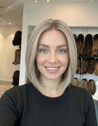 אישה מחייכת חובשת פאת קארה בלונדינית חלקה במראה טבעי בתצוגת פאות.