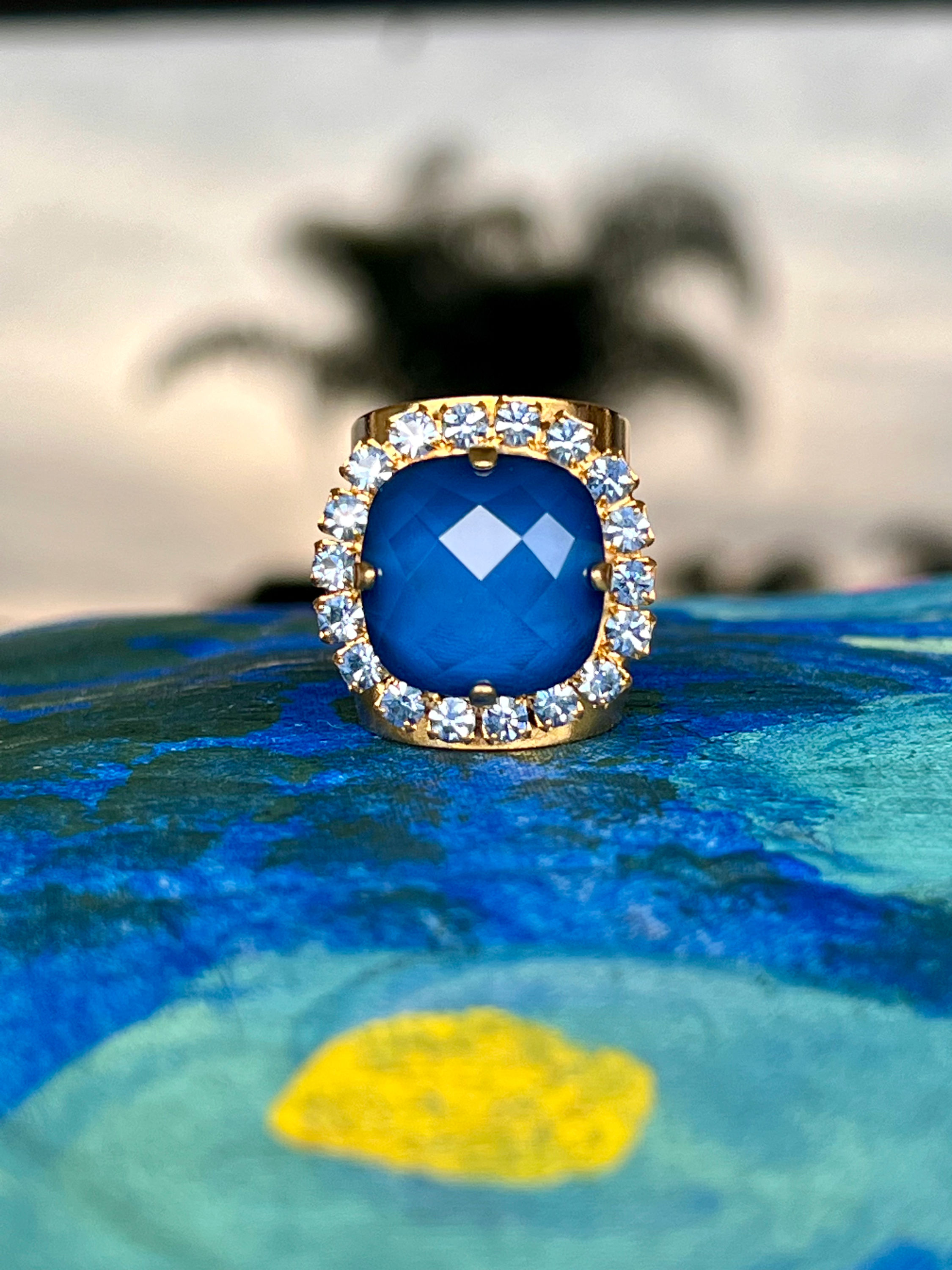Gold Blue Crystal Statement Ring on blue pillow with palm tree