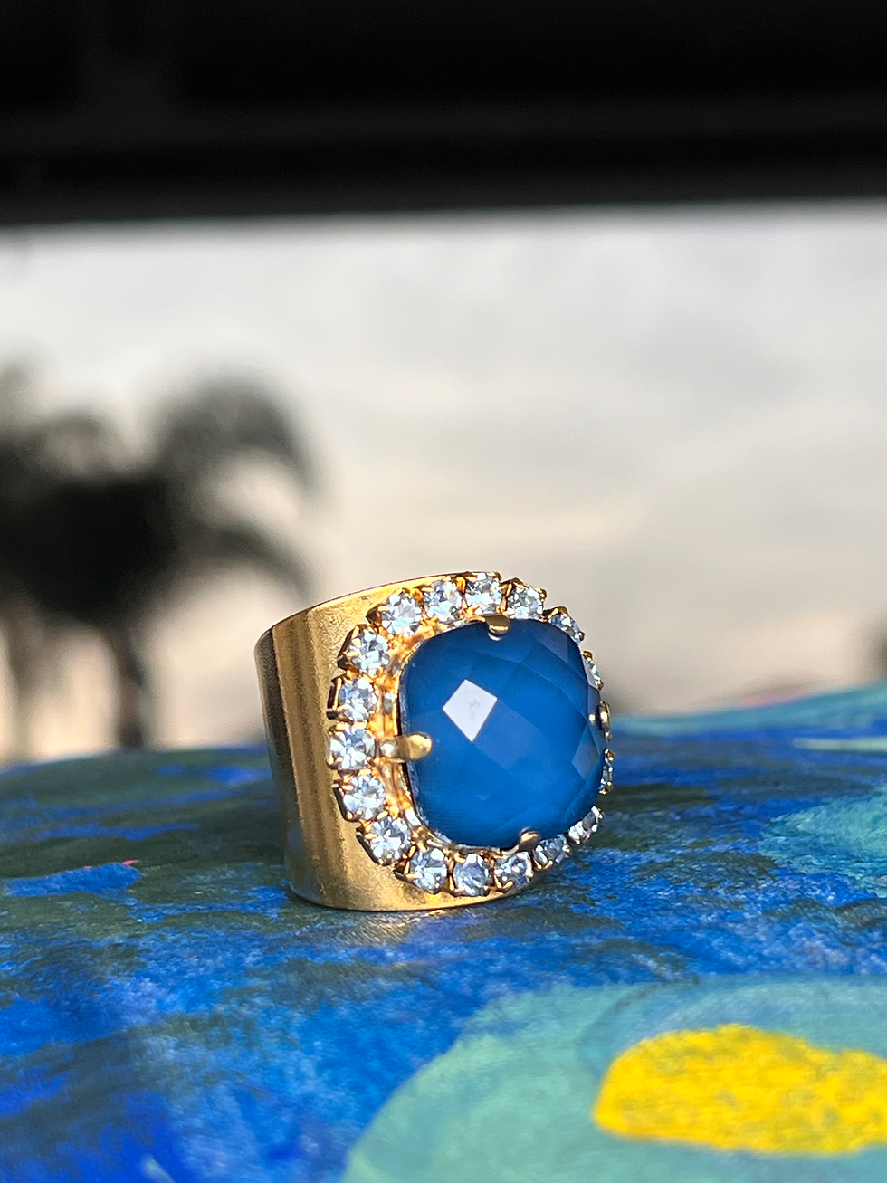 Thumbnail: Gold Blue Crystal Statement Ring on blue pillow with palm tree