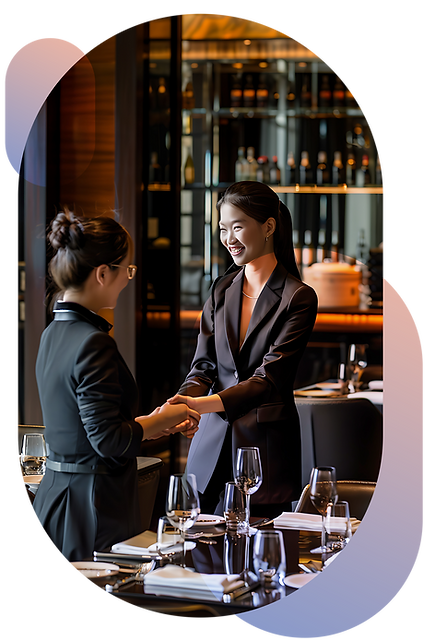 Two professional women shaking hands in an upscale restaurant setting, surrounded by neatl