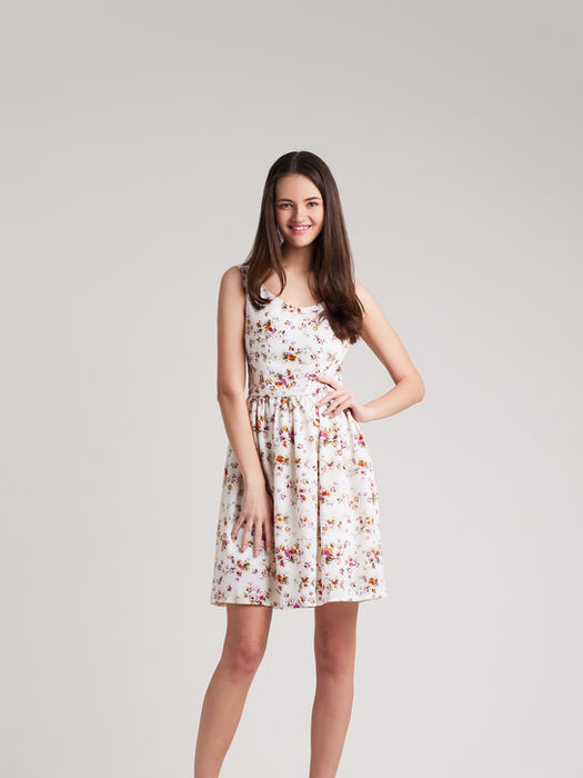 Young woman poses in a floral dress, smiling with her hand on hip. My Site 1