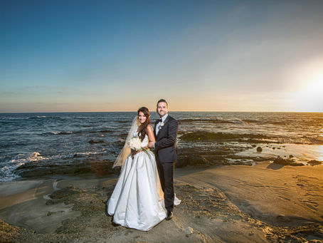 Bride and groom on a rocky beach at sunset