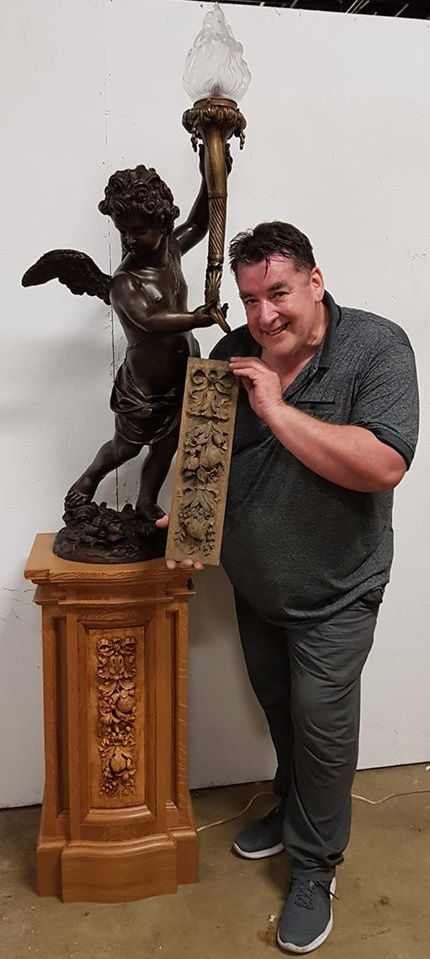 Titanic collector John White and owner of White Star Memories holds up an original newel carving from RMS Olympic in front of the historically accurate bronze replica of Titanic's famous cherub lamp by Alan St. George.