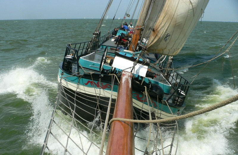 Historic sailing ship Bonnefooi sailing between Rotterdam and Antwerp during a 7-day wind-powered slow travel journey by Fair Ferry. Travelers experience sustainable tourism, life at sea, city-center stays, swimming, sailing participation, and eco-friendly travel across Europe.