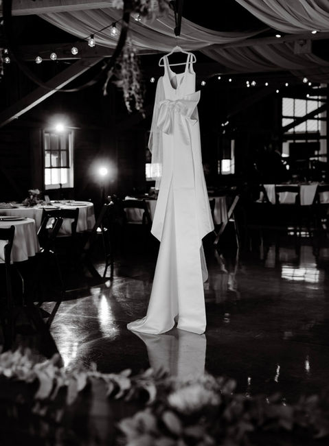 A black and white photo of a wedding dress hanging inside Blue Heron Barn.