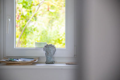 Fensterbank mit dekorativer Büste und Schale vor grünem Ausblick im Apartment Grias Di