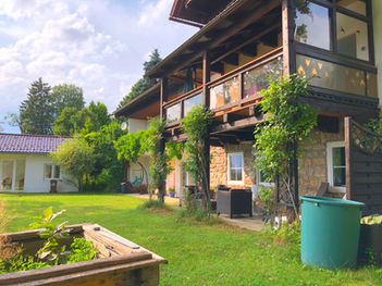 Blick auf Ferienhaus und separates Gartenhaus mit großem Rasen und Bergpanorama
