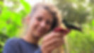 Une jeune femme tient une mangeoire sur laquelle est venu se poser un colibri