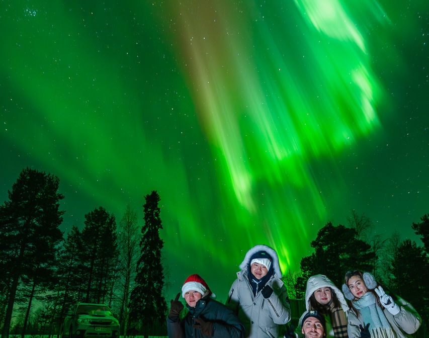 group of tourist and the guide posing with the aurora borealis in the sky