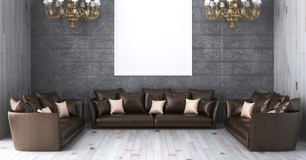 Elegant living room with two brown leather sofas and beige pillows. Ornate gray wall, large blank frame, and chandeliers create a classic feel.