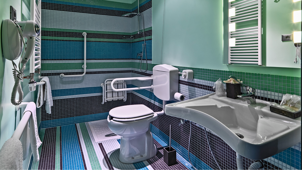 Accessible bathroom with grab bars, a toilet, and a sink. Blue and green mosaic tiles and modern lighting create a clean, functional space.