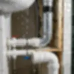 Leaking pipes with red and blue valves in a bathroom sink area, water dripping onto tiles and insulation, conveying urgency.