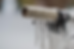 Bike handlebar covered in icicles, with a white grip featuring diamond patterns. Blurred snowy background, creating a cold, crisp mood.