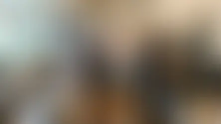 Three people in a kitchen: one washing dishes, another cooking vegetables, and a third getting milk from the fridge. Bright, organized space.