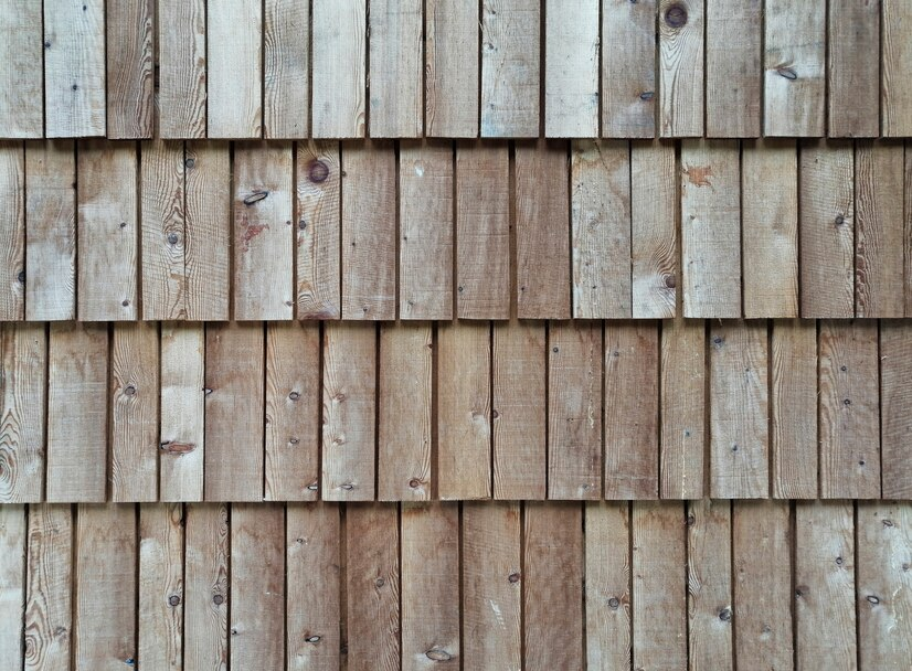Wooden wall with vertical planks in natural brown tones. Textured surface with visible knots and grain patterns. Rustic and earthy feel.