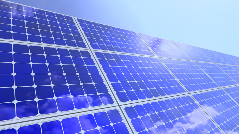 Blue solar panels reflecting a partly cloudy sky. The panels are arranged diagonally against a clear blue background, suggesting clean energy.