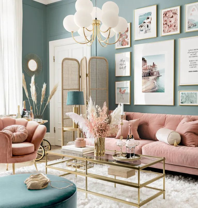 "Charming living room with soft pink furnishings, gold accents, and coastal-themed wall art, combining elegance with modern touches reminiscent of Amalfi Coast-inspired interior design."