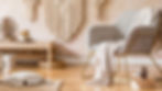 Boho Chic Interior Design featuring a cozy armchair with gold accents, a textured throw blanket, a macramé wall hanging, natural wood furniture, and soft neutral decor elements in a stylish living space.