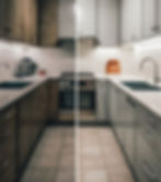 Split-screen kitchen makeover: left side shows dark wood cabinets, right side features modern gray cabinets. Bright lighting, tiled floor.
