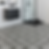 Black and white bathroom with intricate patterned floor tiles, a floating dark vanity with a white countertop, a glass-enclosed shower with black framing, and clean white wall tiles for a modern design.