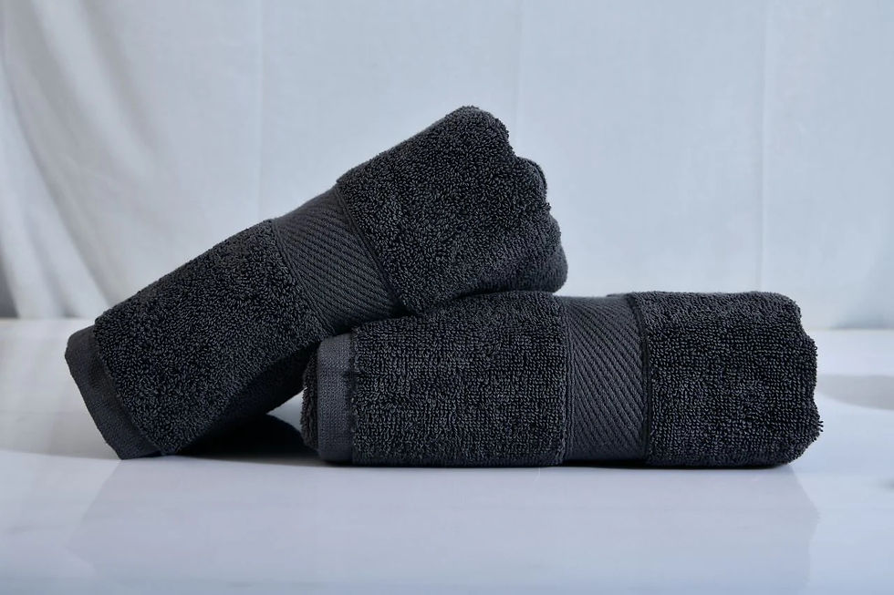 Two dark gray towels neatly stacked on a white surface against a light gray background, creating a calm and tidy atmosphere.