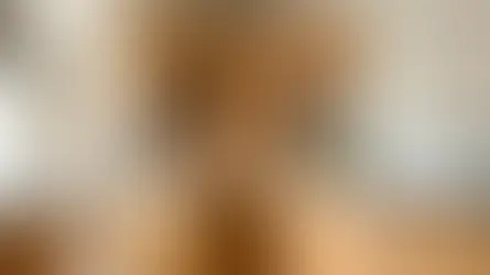 Modern kitchen with wooden cabinets, white countertops, and a potted basil. Tomatoes on a cutting board, and olive oil by the sink. Bright and tidy.