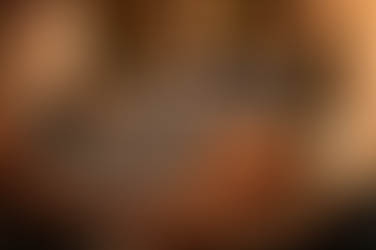 Child sleeping on a couch, covered with a blue blanket. An adult tucks them in. Warm lighting creates a cozy, peaceful atmosphere.