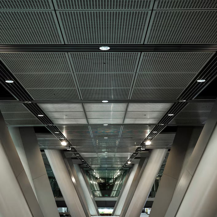 Modern architectural interior with V-shaped beams, overhead grid ceiling, and soft lighting. The setting is industrial and sleek.