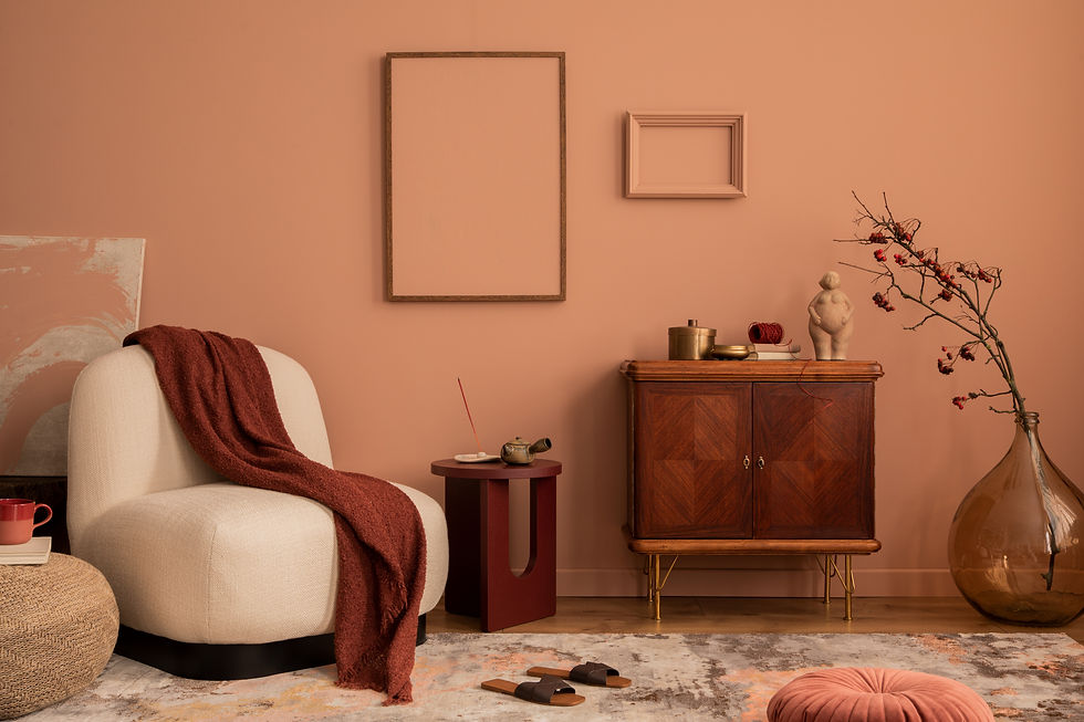 Cozy room with a cream chair, red blanket, brown cabinet, and dried branch in a vase. Peach walls, abstract rug, warm and inviting mood.