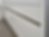 Close-up of glossy white kitchen cabinet drawers with metal handles, reflecting light. Floor is visible. Modern and minimalistic design.