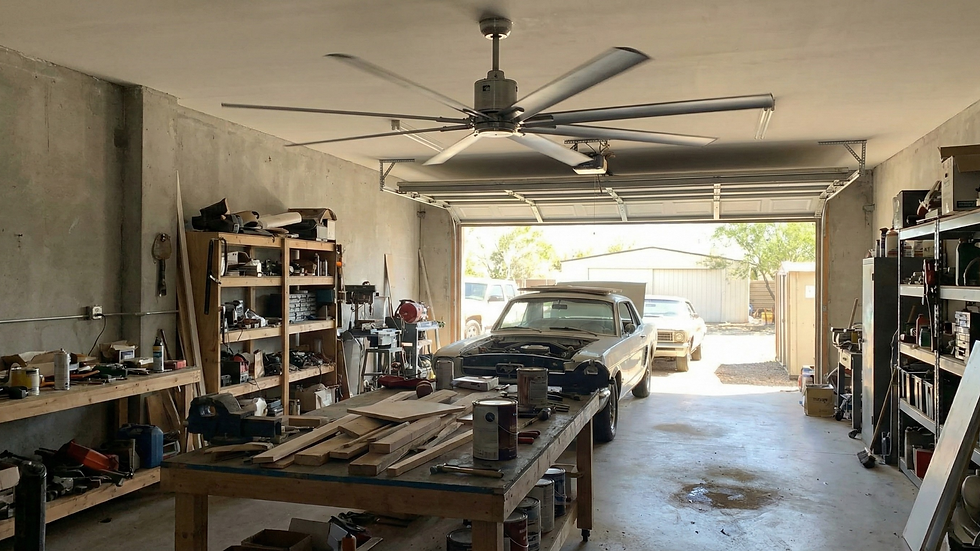 A garage with a classic car under repair, workbenches, shelves with tools, and a large fan above. The open door shows a bright day outside.