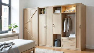 Light wood wardrobe with open shelves, hanging clothes, and stacked towels. A plant sits on the window ledge. Calm and tidy bedroom scene.