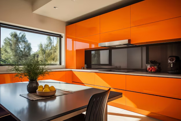 Modern kitchen with bright orange cabinets, a table with lemons and a plant, large window with trees outside. Sunlit and sleek.