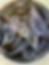 A patterned and dark fabric lies inside a metallic washing machine drum, highlighting texture and colors under bright light. No text visible.
