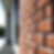 Close-up of a red brick wall with sunlight casting shadows, framed by a modern window, outdoors. Bright and clean architectural detail.