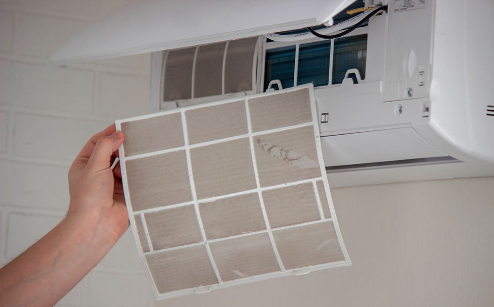 Hand removes dusty filter from a wall-mounted air conditioner against a light background, emphasizing maintenance and cleanliness.