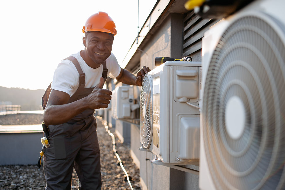 Man in orange hard hat gives thumbs up while servicing rooftop AC unit. He's smiling, wearing a white shirt and overalls. Sunny day.
