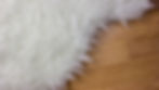 Close-up of a fluffy white rug texture on hardwood flooring, perfect for adding comfort to a living room.
