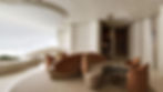 A modern living space showcasing a stunning curved interior design. The room features smooth, flowing lines in the walls and ceiling, with organic, curved furniture that complements the overall aesthetic. The curved sofa, soft beige tones, and circular seating arrangement create a harmonious and elegant atmosphere, highlighting the sophisticated use of curves in the architecture and decor.