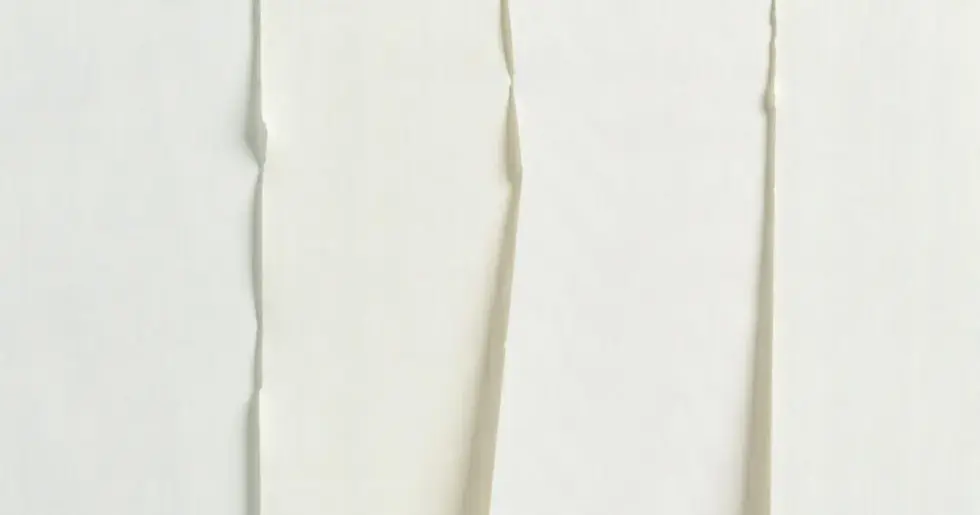 A selection of white paint swatches for kitchen cabinets, displayed under different lighting conditions.